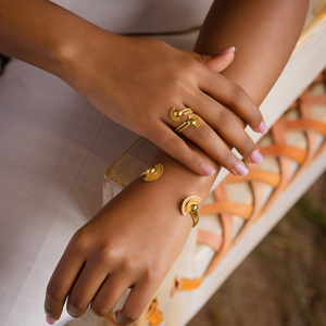 Gold-plated cuff bracelet with textured crescent charm and round ends on wrist