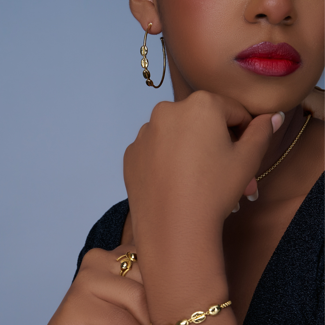 Gold hoop earring with dangling textured oval charms, open circular shape