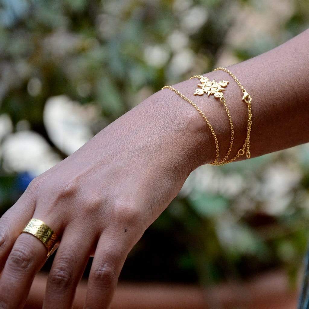 A Model's Hand Wearing Yenaé 14K Gold Plated Lalibela Cross Necklace As Bracelet 